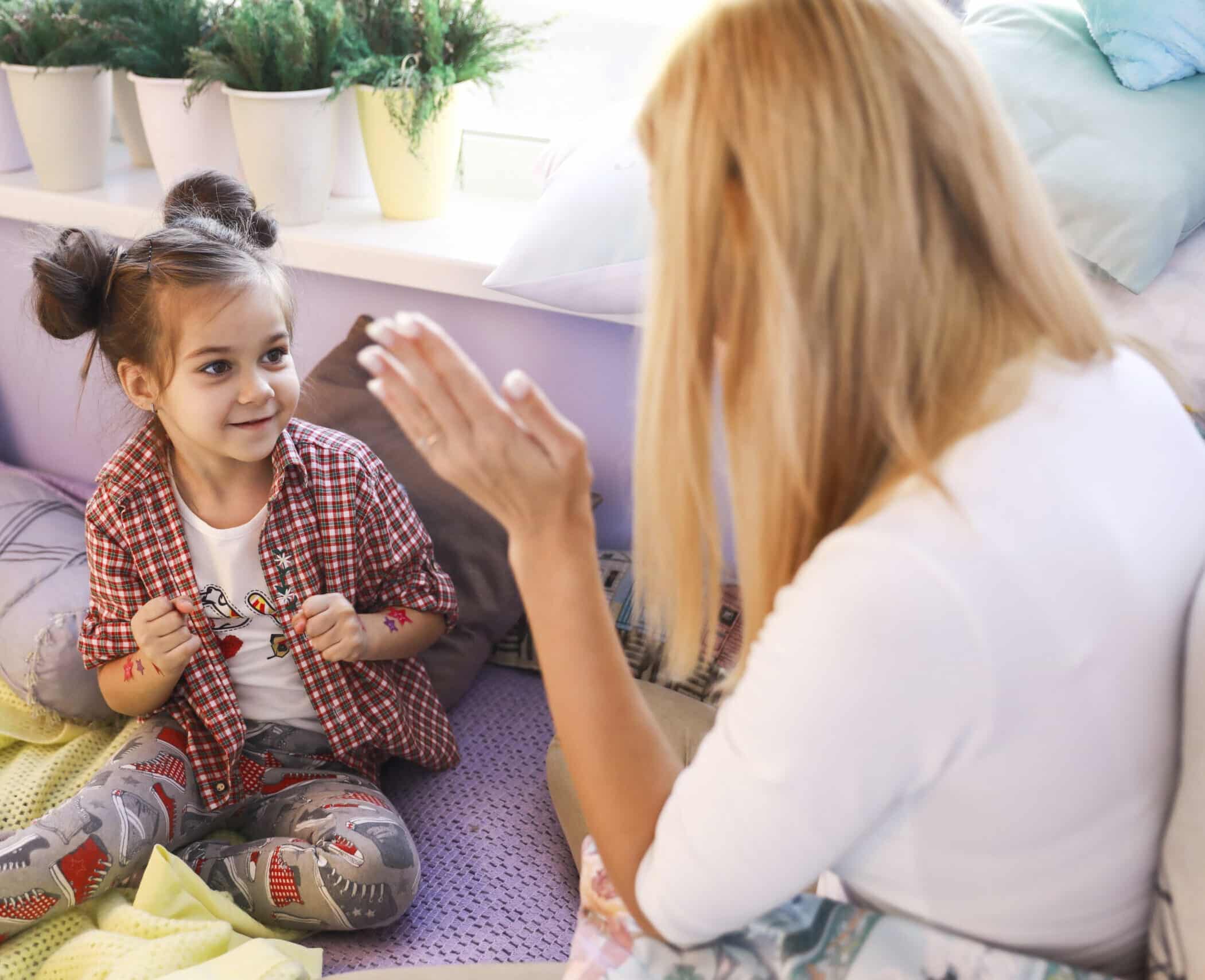 Young girl is playing with mother near the window